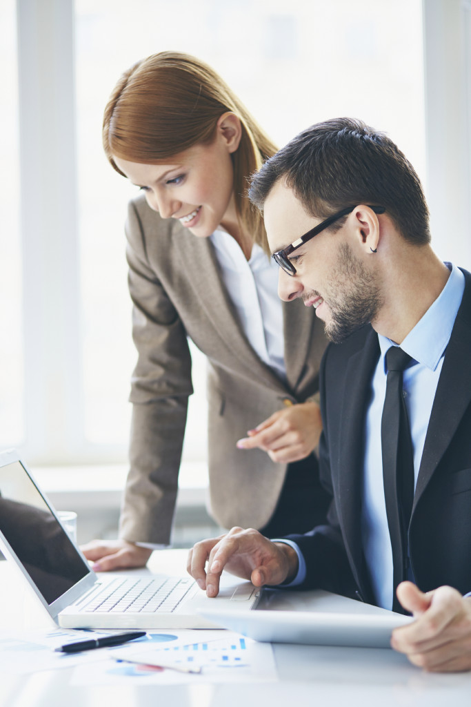 Image of two young business partners using laptop at meeting